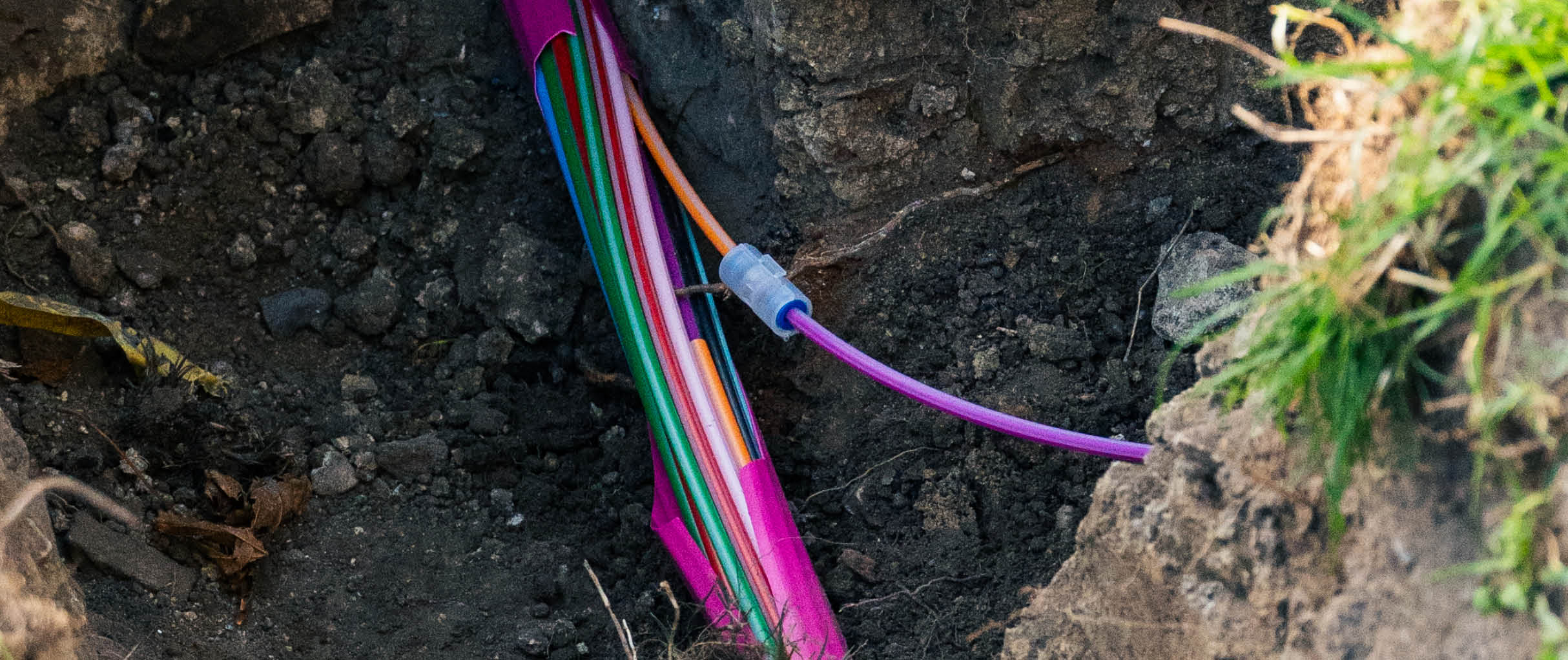 Offener Kabelgraben mit Glasfaserkabel während der Verlegung im Rahmen von Tiefbauarbeiten für den Glasfaserausbau.